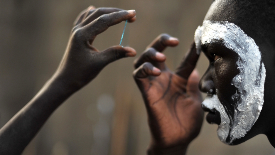 A South Sudanese boy belonging to a cultural dance group uses moistened ground chalk to mark traditional tribe paintings on his face before his group performed at a cultural center in Juba on Jan. 16, 2011.